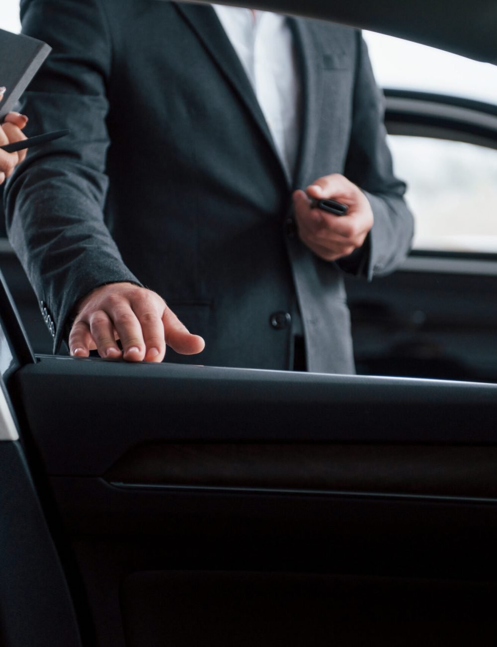 Photo from the inside of vehicle. Female customer and modern stylish bearded businessman in the automobile saloon.
