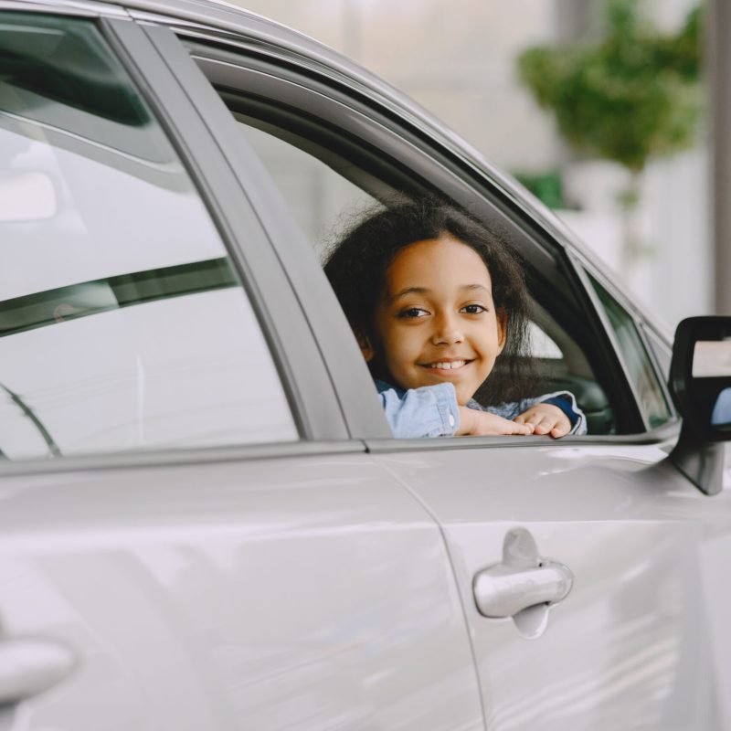 Pretty little girl looking at camera. Child in a car salon.